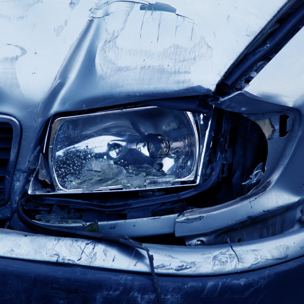 Damaged front headlight of a car with visible dents and broken glass.